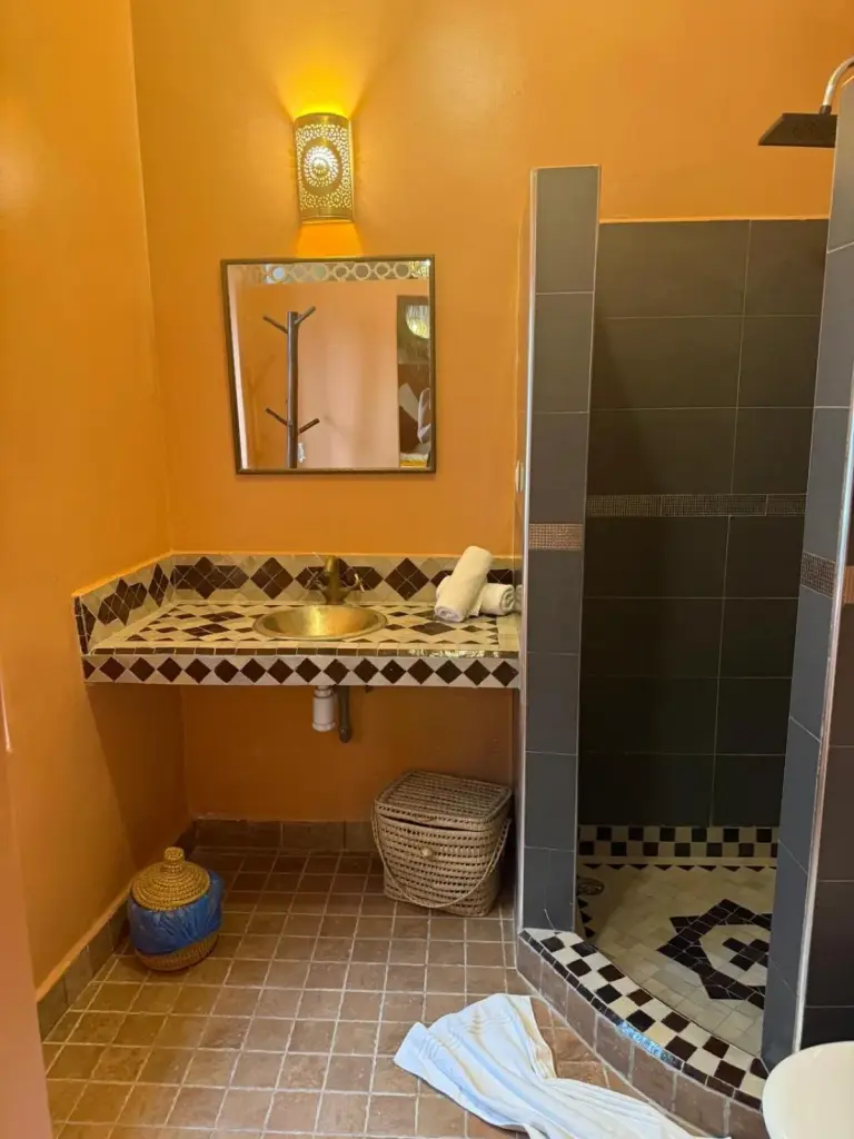 Badezimmer im Riad DIHYA & Rooftop Pool in Marrakesch mit orangefarbenen Wänden und Duschbereich