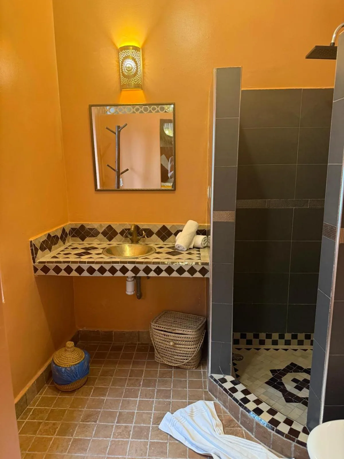 Badezimmer im Riad DIHYA & Rooftop Pool in Marrakesch mit orangefarbenen Wänden und Duschbereich