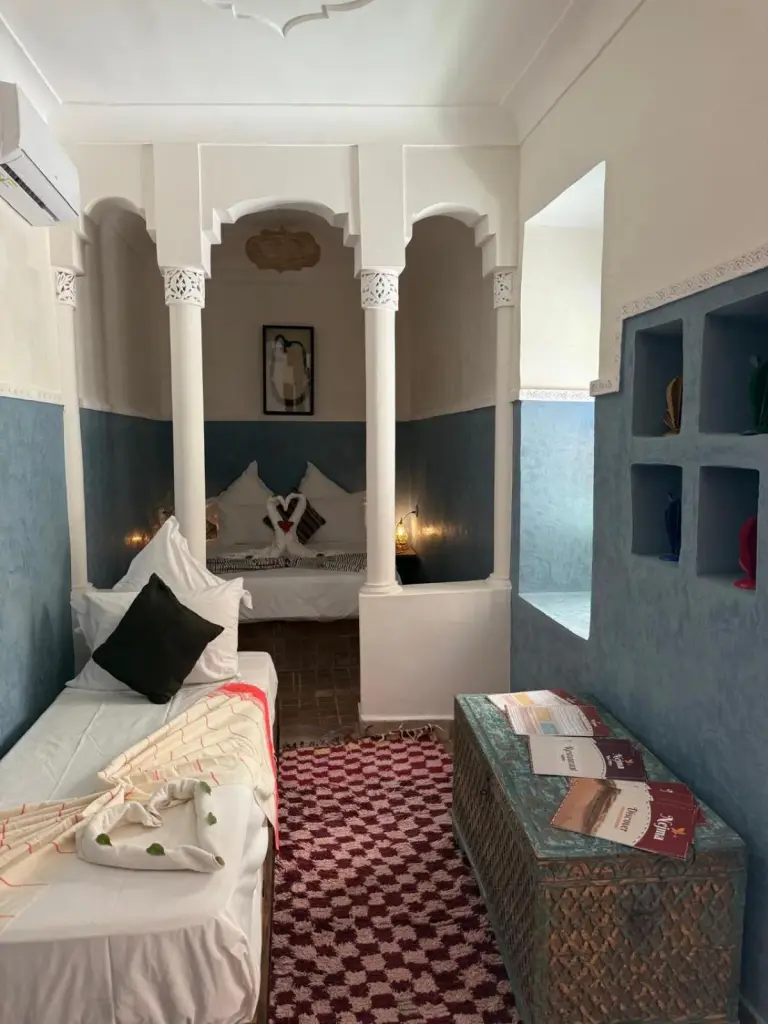 Sitz- und Schlafbereich mit zwei Betten im Riad DIHYA & Rooftop Pool in Marrakesch mit Bögen und blauen Wänden