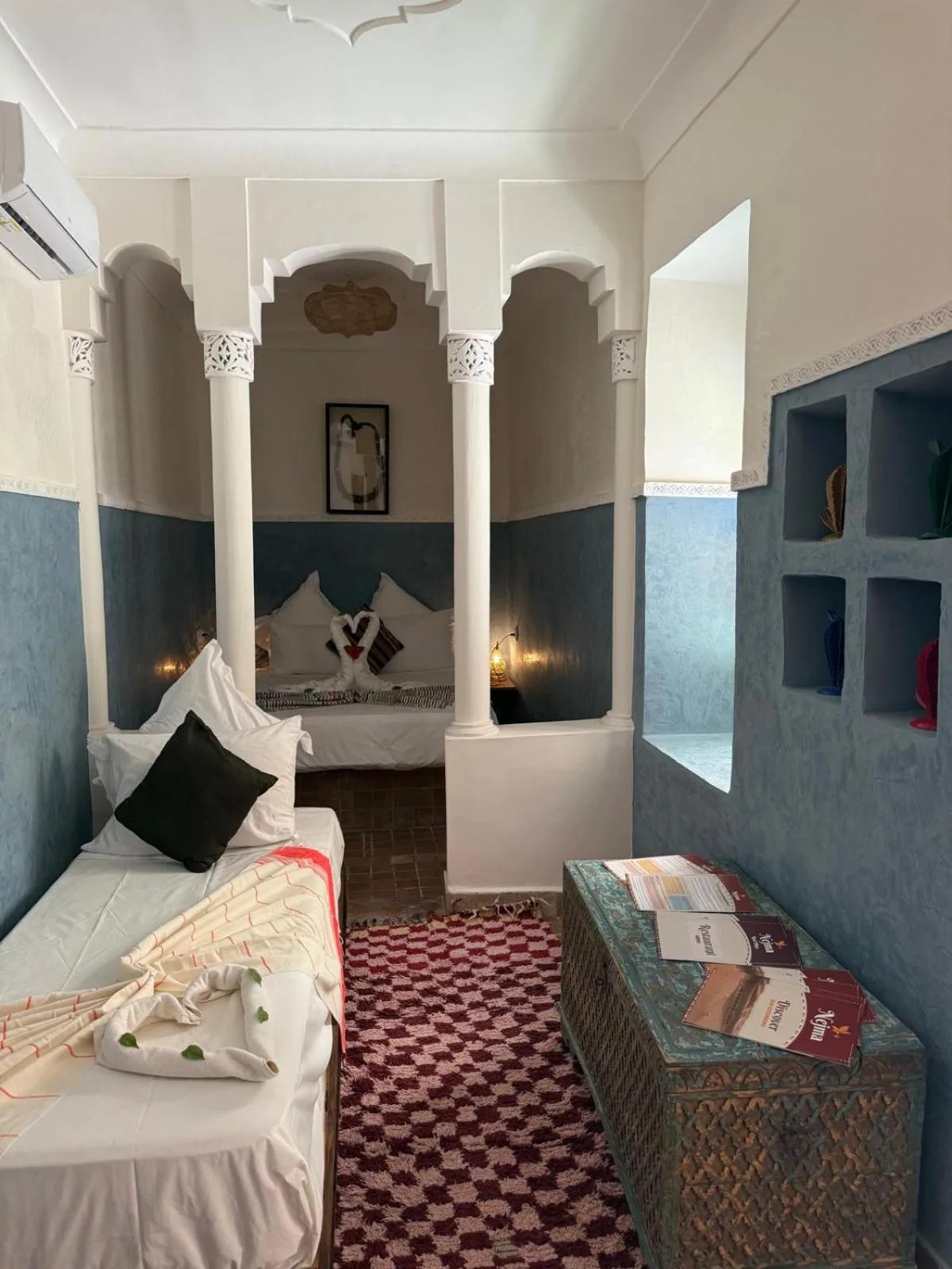 Sitz- und Schlafbereich mit zwei Betten im Riad DIHYA & Rooftop Pool in Marrakesch mit Bögen und blauen Wänden