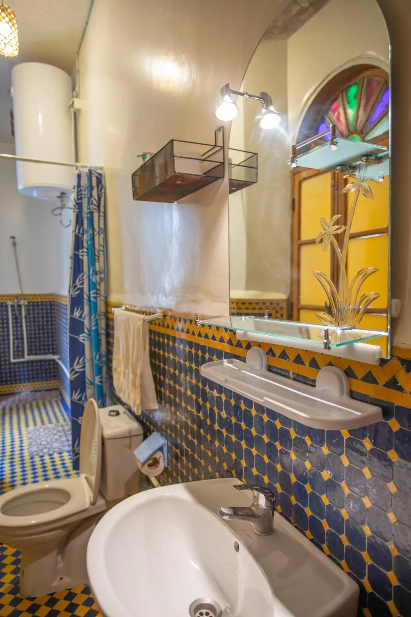 Baño en Riad Fes iline Medina en Fes con paredes de azulejos estampados, lavabo, espejo, inodoro y zona de ducha