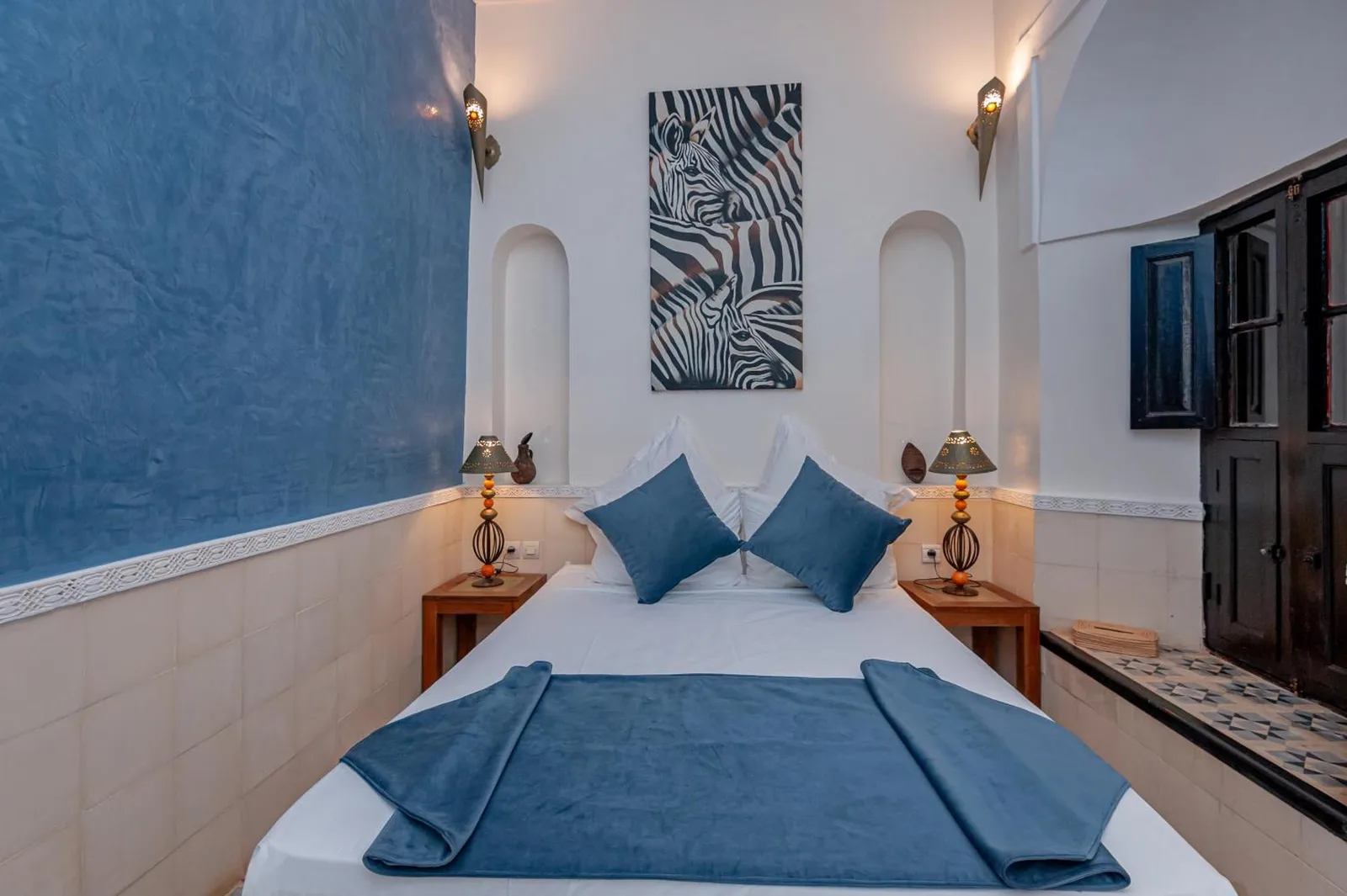 Doppelzimmer im Riad GUENAOUA Jacuzzi & Rooftop in Marrakesch mit Zebra-Kunstwerk und blauer Bettwäsche