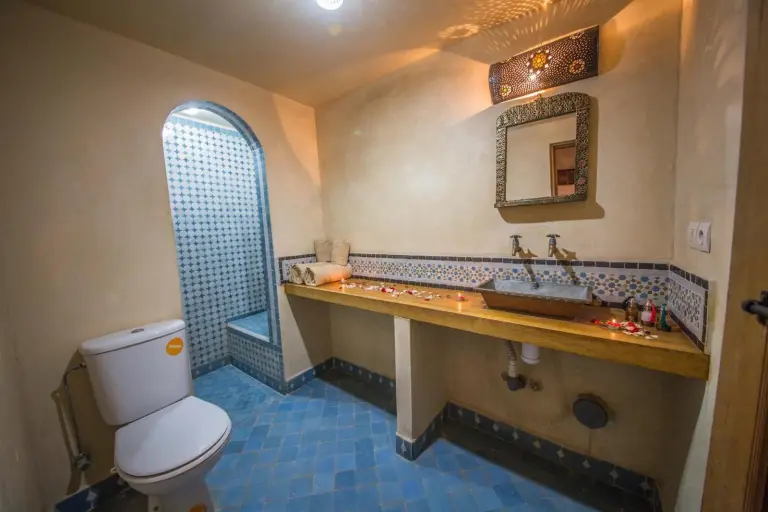 Baño en Riad Gzira Fez en Fes con lavabo de piedra, borde de mosaico y entrada de ducha arqueada