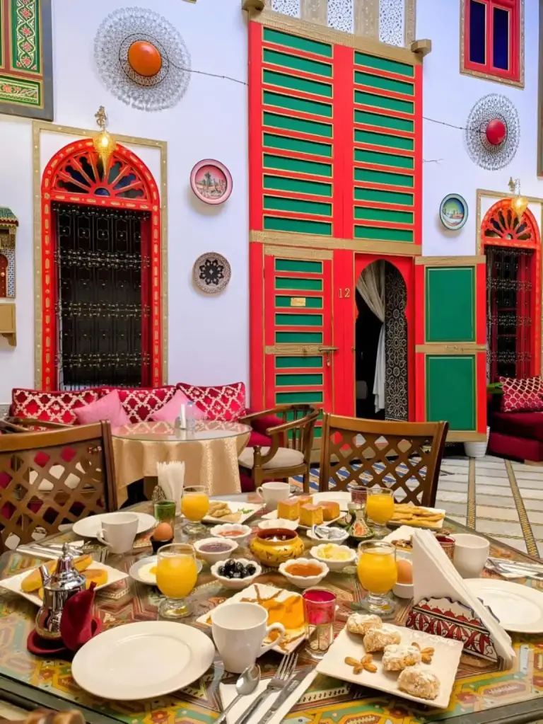 Zona de desayuno en Riad Lhaj Luxury Palace en Fes con asientos tradicionales en el patio y desayuno servido