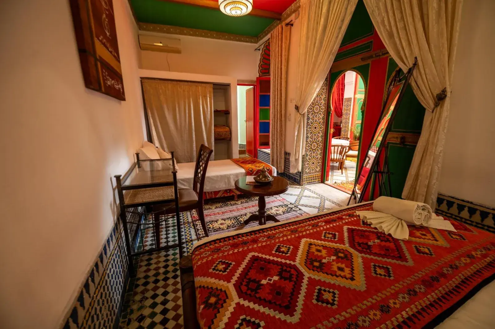 Habitación de huéspedes en Riad Lhaj Luxury Palace en Fes con cama, escritorio, cortinas y acceso a la terraza