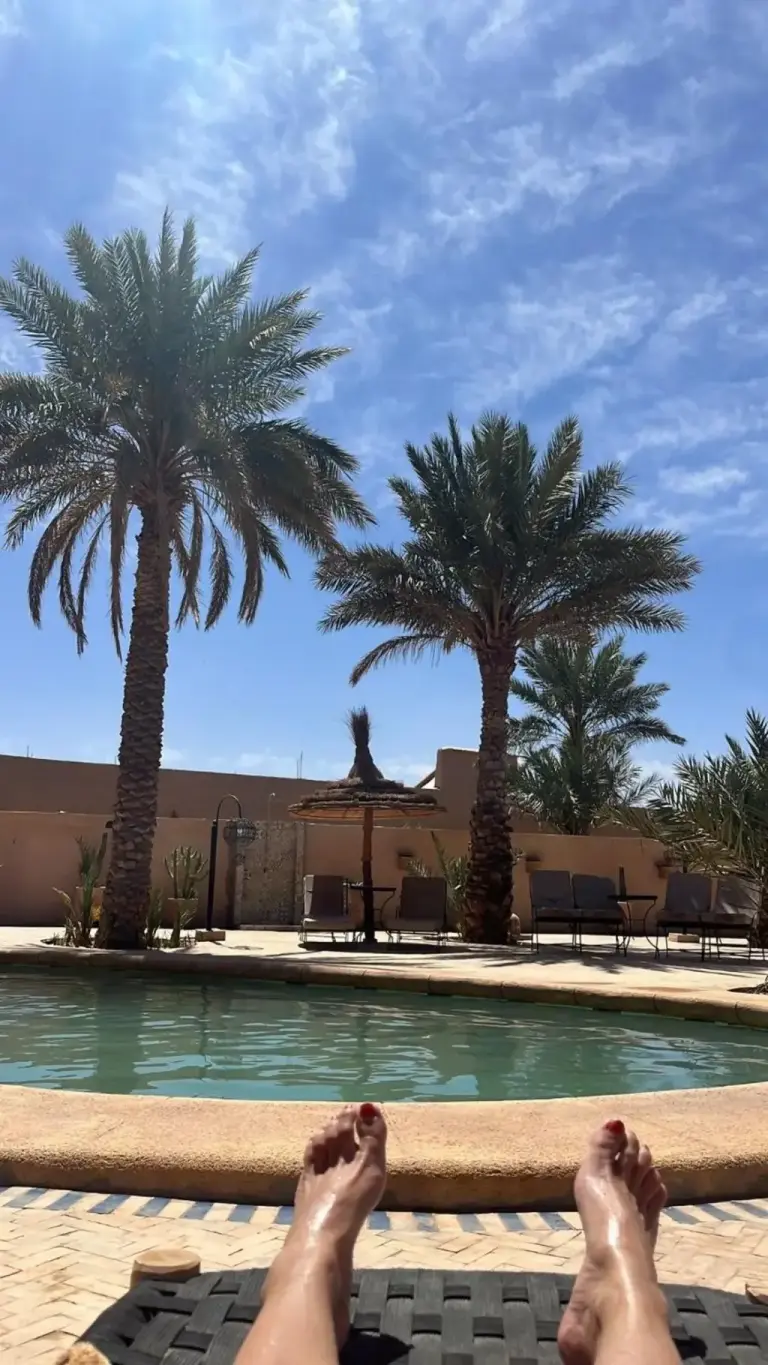 Relaxing by the pool at Riad Suerteloca Merzouga under palm trees