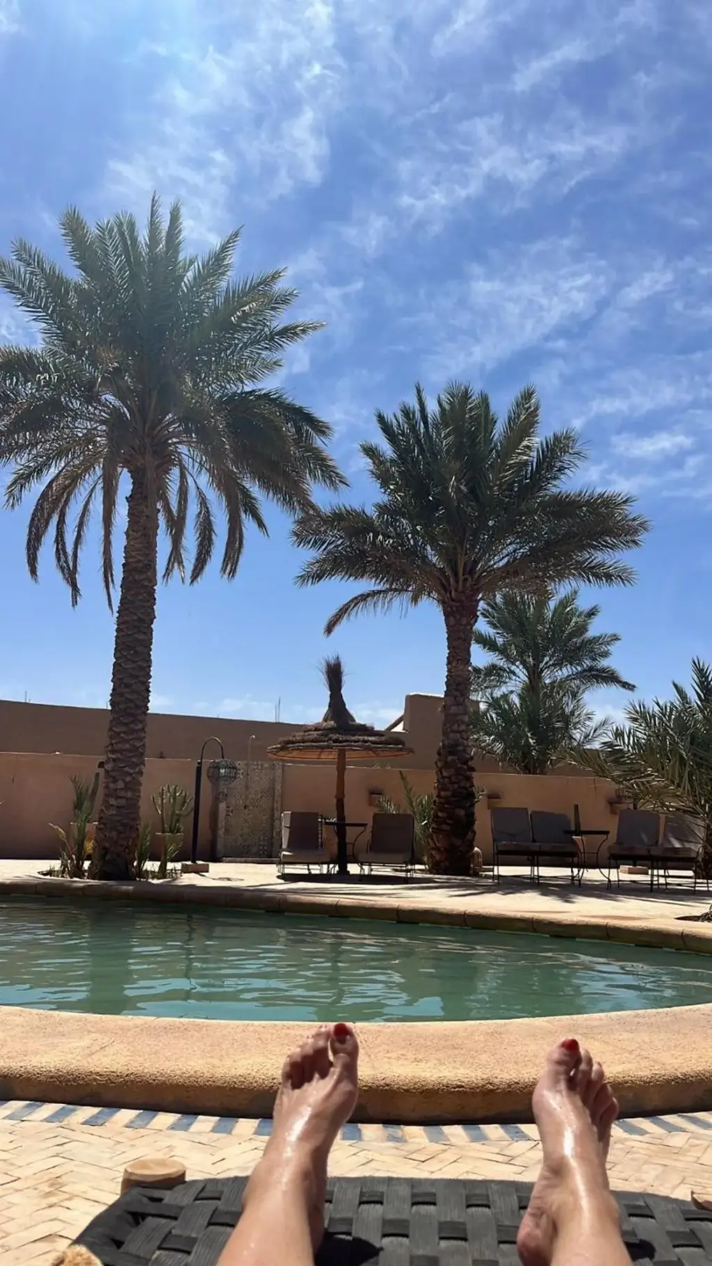 Relaxing by the pool at Riad Suerteloca Merzouga under palm trees