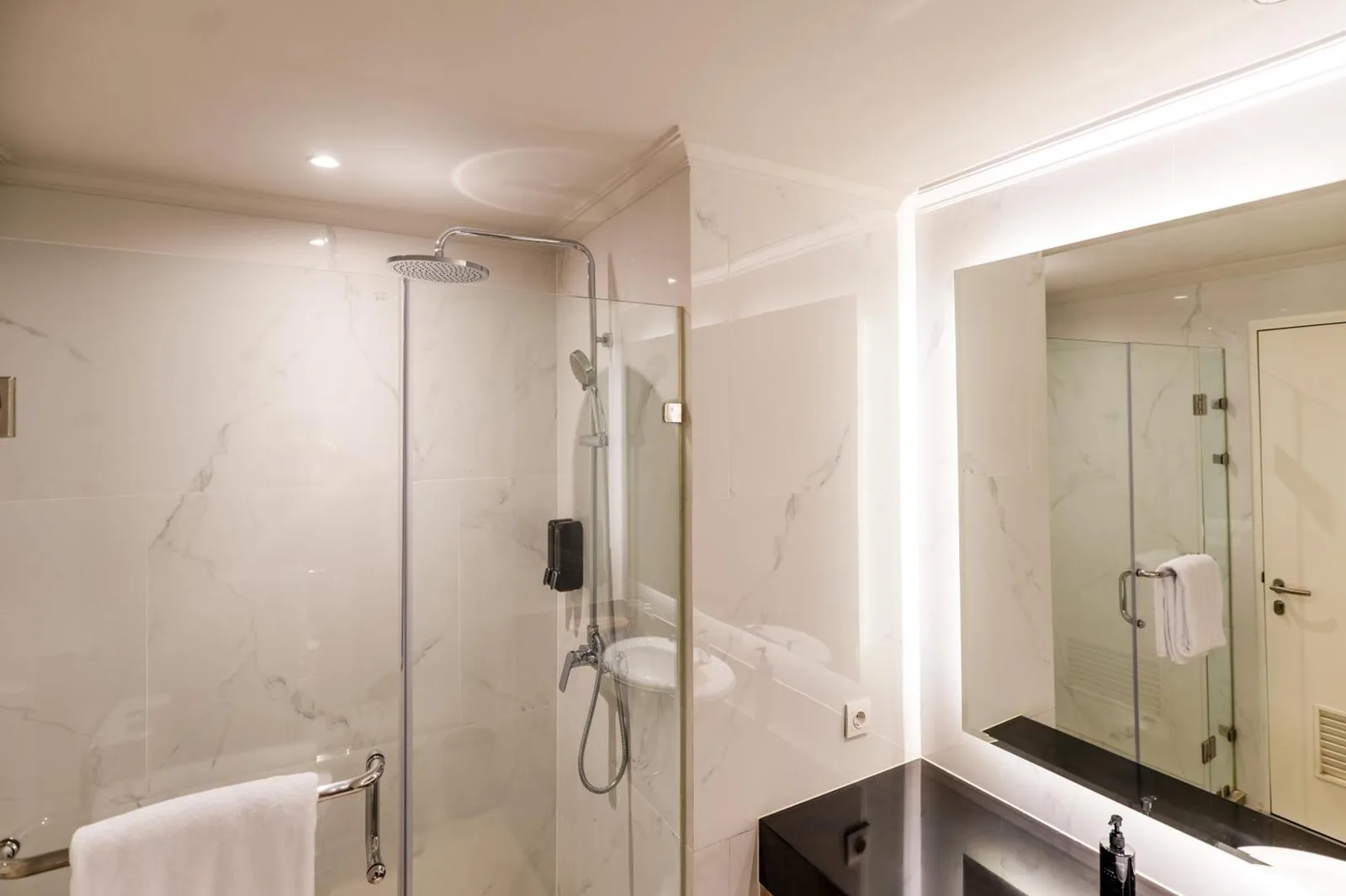 Salle de bains moderne au Rich Palace Hotel Surabaya avec douche, vasque et miroir éclairé