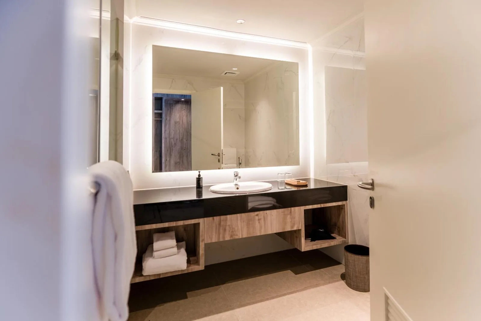 Vasque de salle de bains au Rich Palace Hotel Surabaya avec lavabo, miroir et rangement ouvert