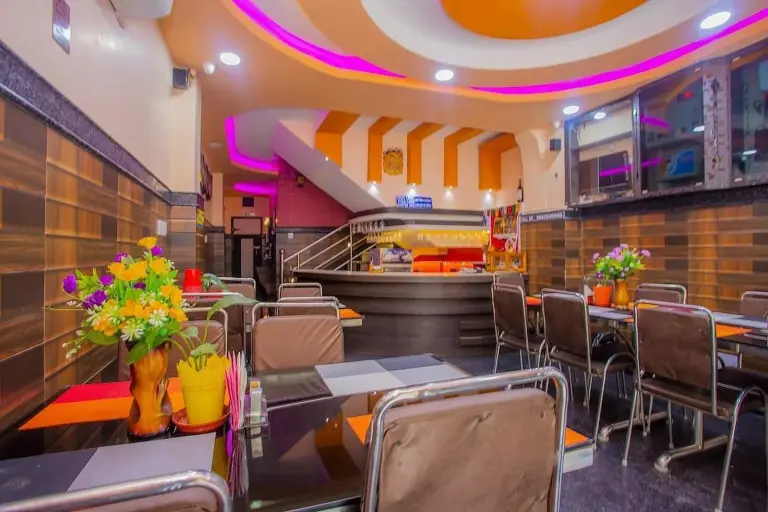 Salle à manger du restaurant au RINGJI PALACE à Birtamod avec tables, chaises, fleurs et éclairage d’ambiance chaleureux.