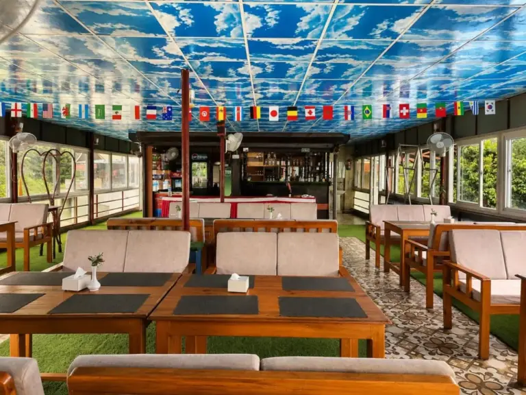 Zona de comedor en River Side Hotel Pvt Ltd en Bandipur con mesas de madera, asientos y techo decorativo