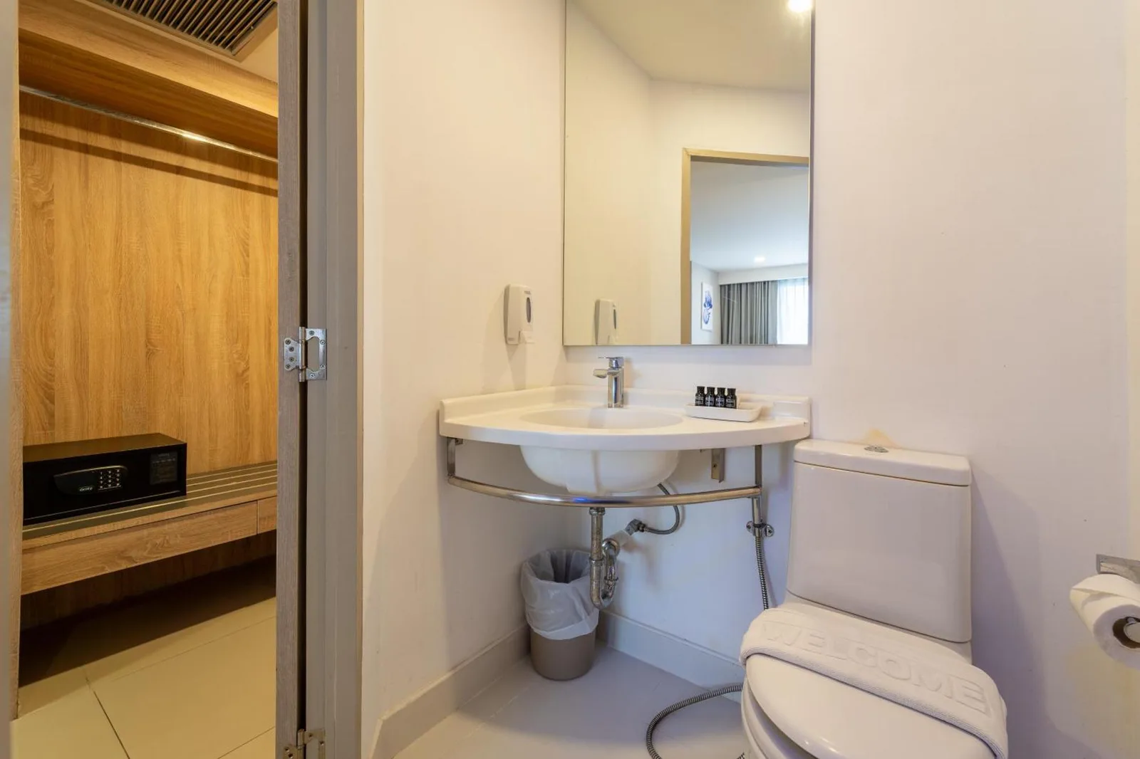 Rodina Beach Hotel Pattaya bathroom with sink, mirror, toilet, and modern white finishes
