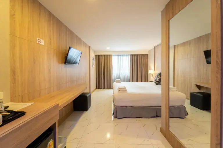 Rodina Beach Hotel Pattaya bedroom interior with bed, wall-mounted TV, desk, and mirrored wardrobe