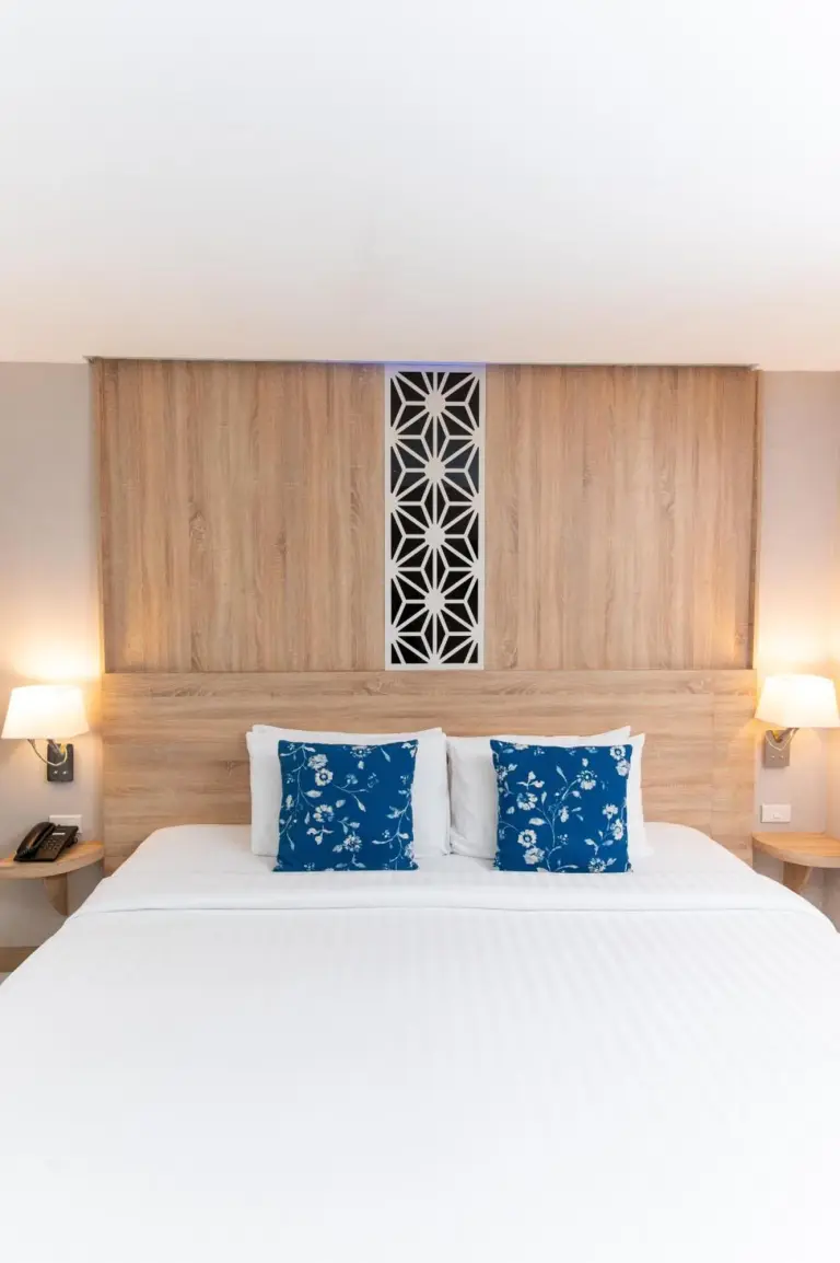 Rodina Beach Hotel Pattaya double bed with blue patterned pillows and wooden headboard
