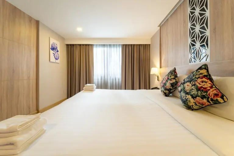 Rodina Beach Hotel Pattaya king bed with floral pillows, bedside lamps, and curtains