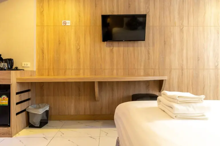 Rodina Beach Hotel Pattaya room with wooden work desk, wall-mounted TV, and bed