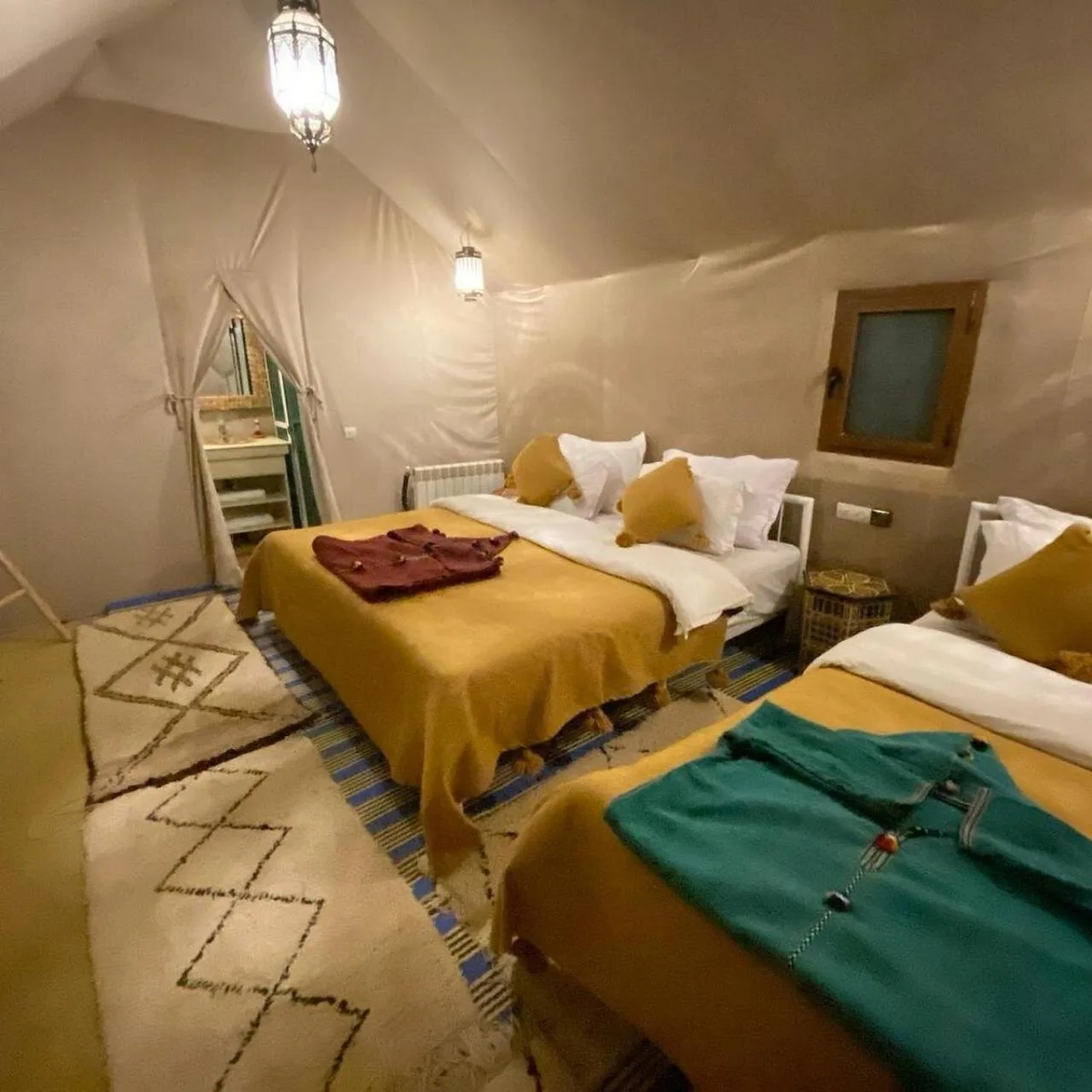 Rosara Luxury Camp in Merzouga tent room with several beds and striped traditional bedding