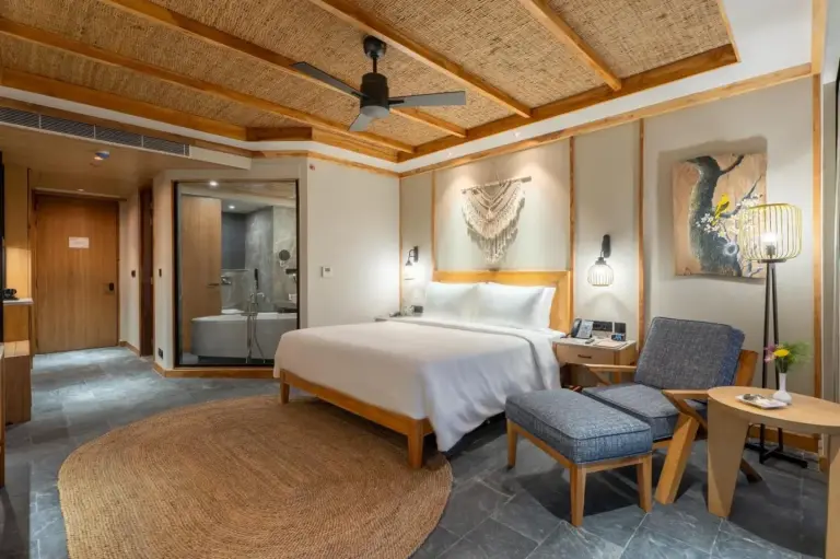 Habitación deluxe en Royal Tulip Chitwan Nepal en Sauraha con cama, zona de estar y acceso al baño