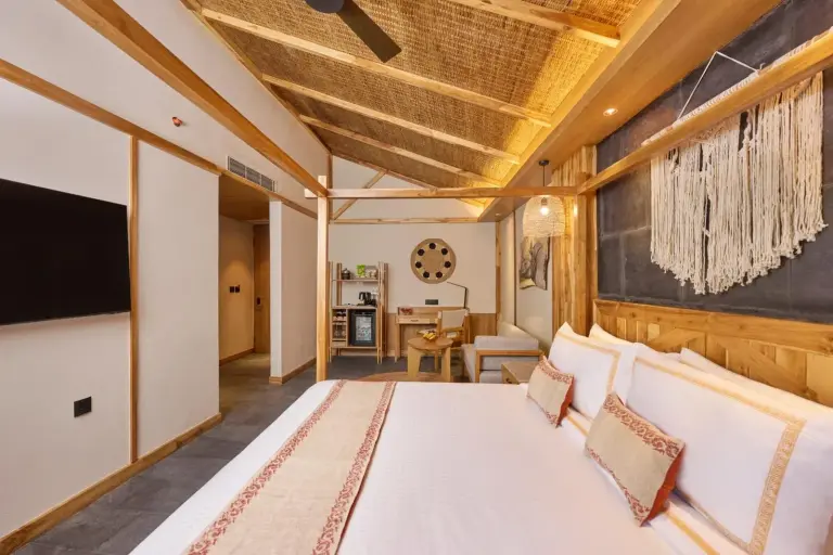 Interior de una habitación de huéspedes en Royal Tulip Chitwan Nepal en Sauraha con una cama king y una decoración cálida y lujosa
