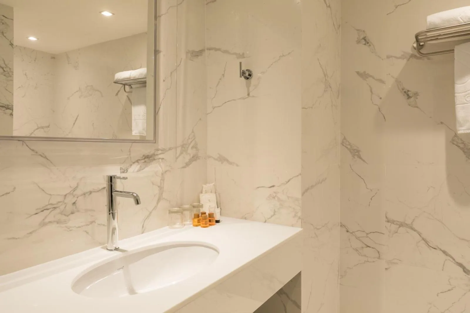 Waschbecken- und Waschtischbereich im S Ram Leisure Hotel Bangkok mit Pflegeprodukten und Wänden in Marmoroptik
