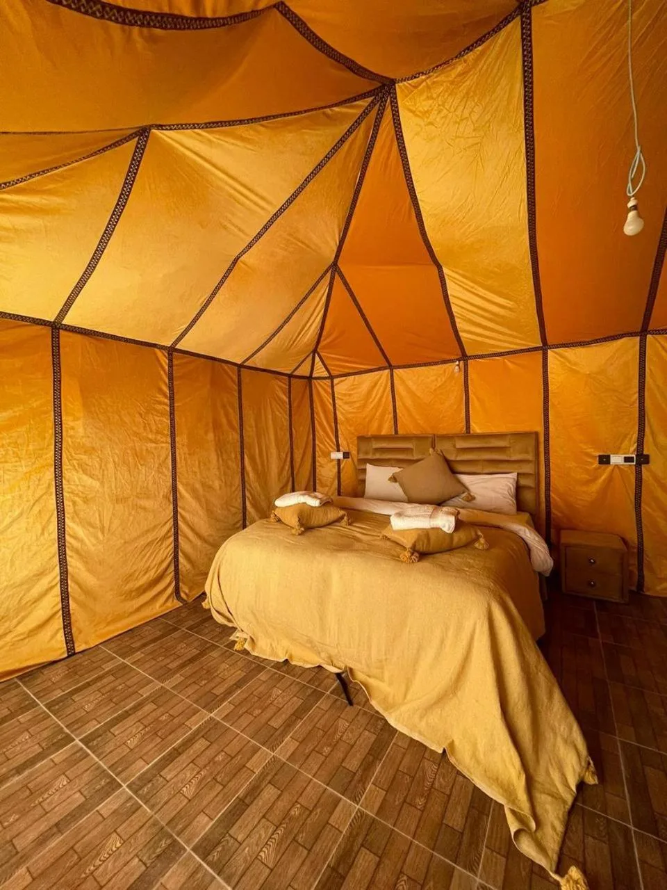 Double bed tent room at Safari Desert Camp in Merzouga with warm orange canvas walls and rustic flooring