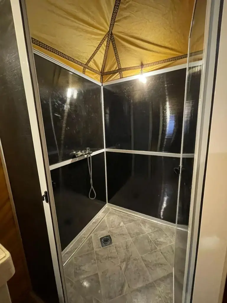 Private shower room at Safari Desert Camp in Merzouga with tiled walls and enclosed wet area