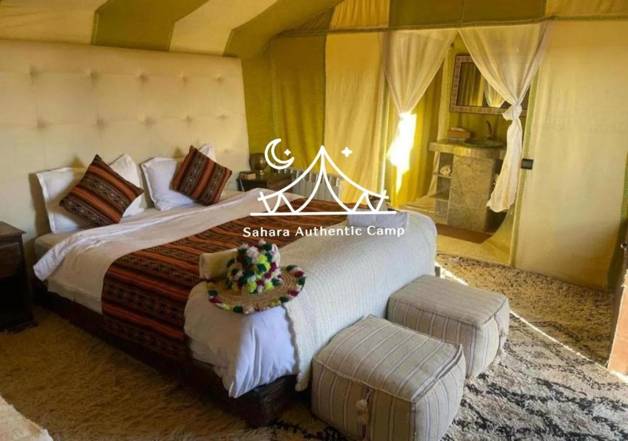 Habitación Deluxe en Sahara Authentic Camp en Merzouga con una cama grande, detalles estampados y elegante decoración de tienda.