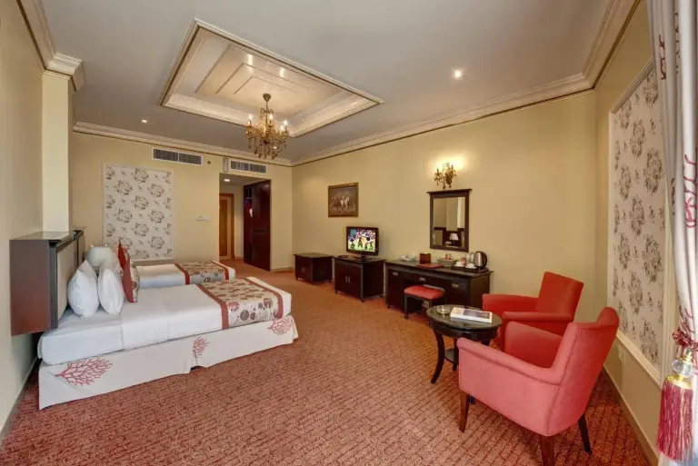 Suite twin à Sahara Beach Resort & Spa Sharjah avec deux lits et fauteuils rouges
