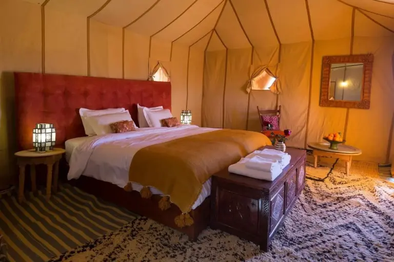 Spacious suite bedroom at Sahara Elegance Camp in Merzouga with a plush bed, rugs, and warm Moroccan-style decor