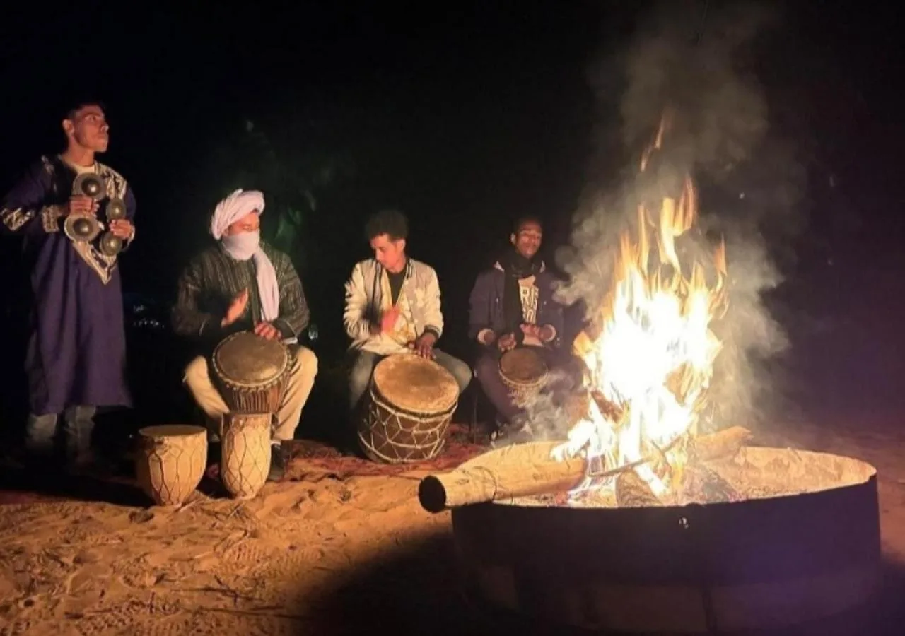 Trommler, die nachts um ein Lagerfeuer im Sahara horizon Camp in Merzouga auftreten.