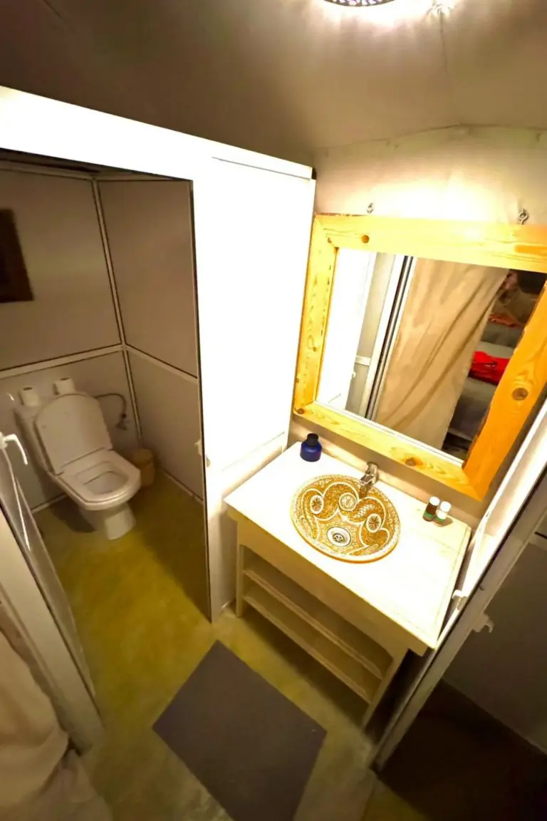 Bathroom vanity and toilet inside Sahara Luxe Camp in Merzouga with a decorative sink and compact private restroom.