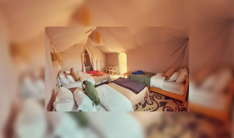Large family tent at Sahara Luxe Camp in Merzouga with several beds, warm lighting, and traditional furnishings.