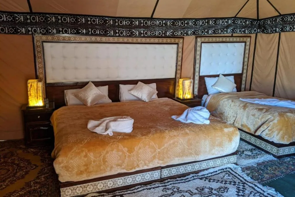 Family tent room at Sahara Relax Camp in Merzouga with a double bed and single bed dressed in gold bedding