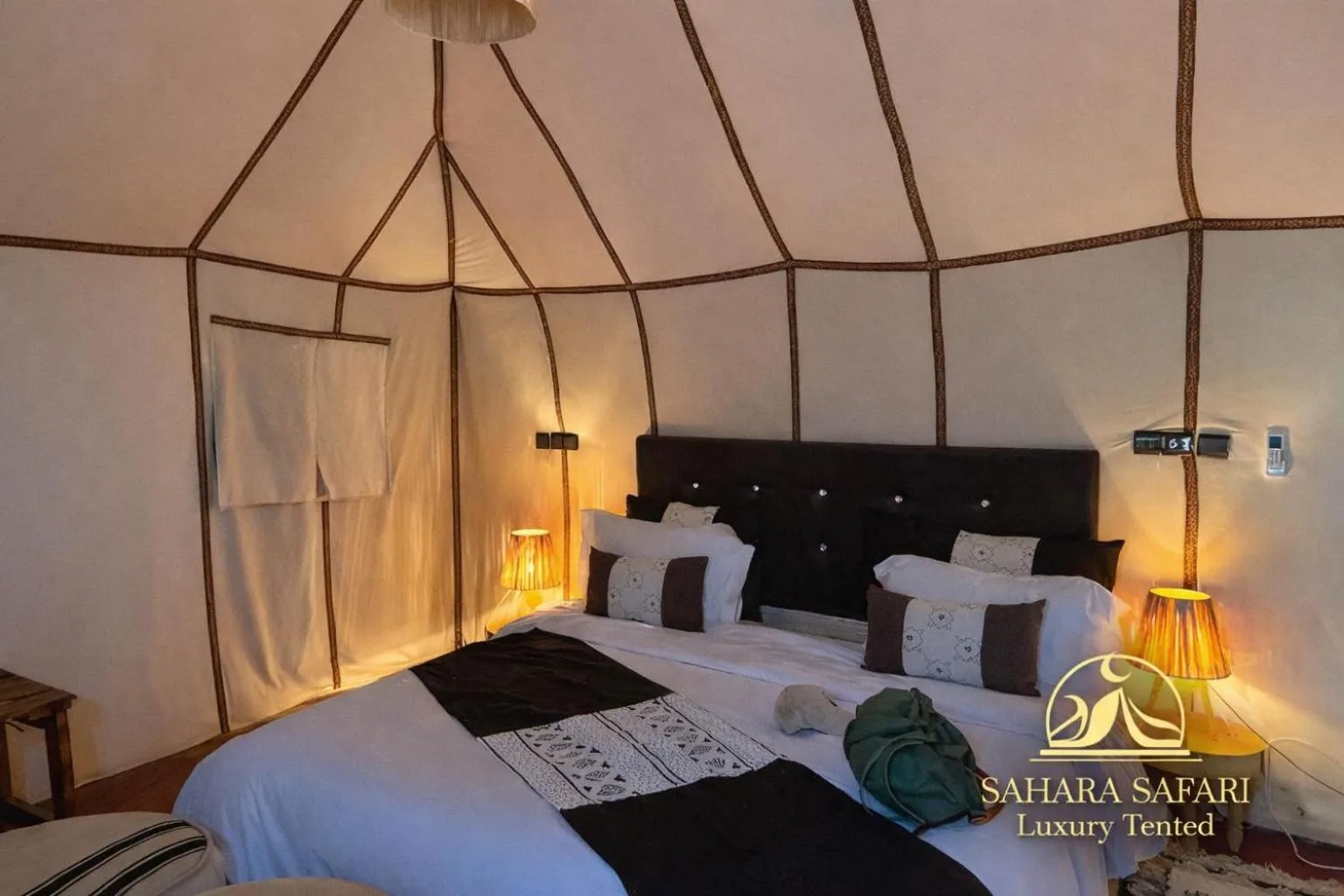 Elegantes Queen-Zeltzimmer im Sahara Safari Luxury Camp & Activities in Merzouga mit großem Bett, Laternenlicht und weichen Textilien.