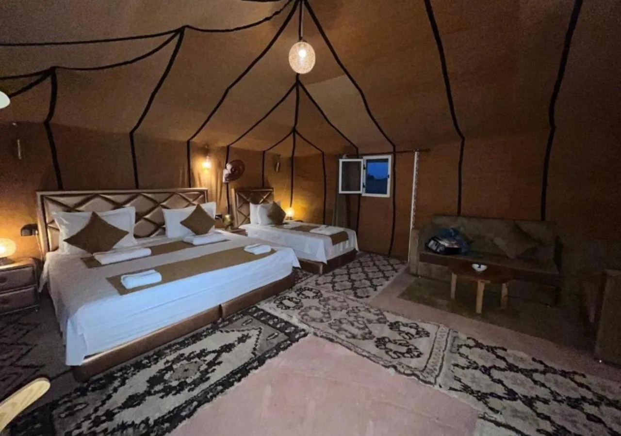 Sahara Soul Luxury Camp in Merzouga deluxe tent suite with double bed, twin bed, and cozy seating area.