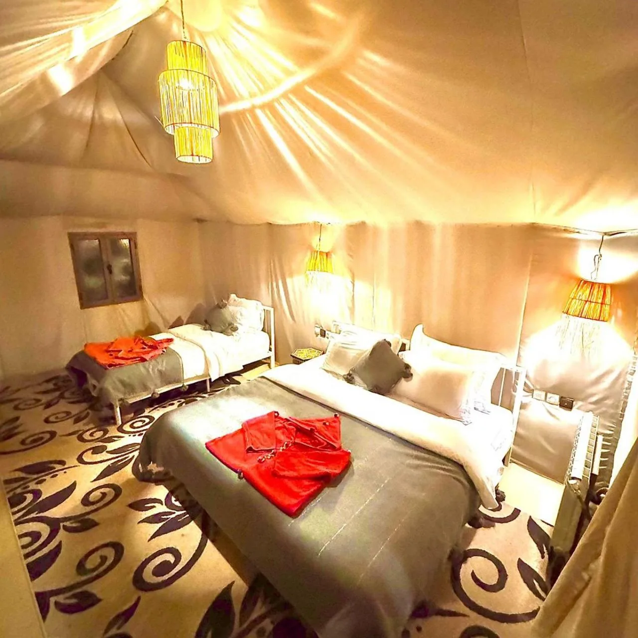 Sahara Soul Luxury Camp in Merzouga luxury tent interior with elegant bedding, patterned carpet, and ambient lanterns.