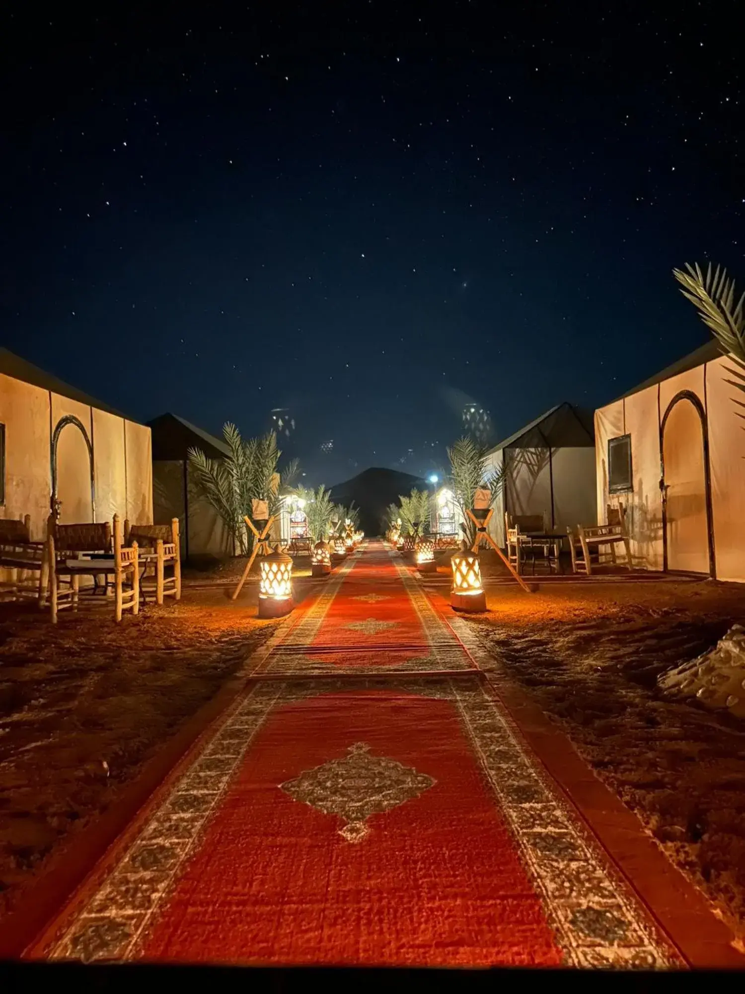 Night view of the illuminated walkway at Sahara Tours luxury camp in Merzouga