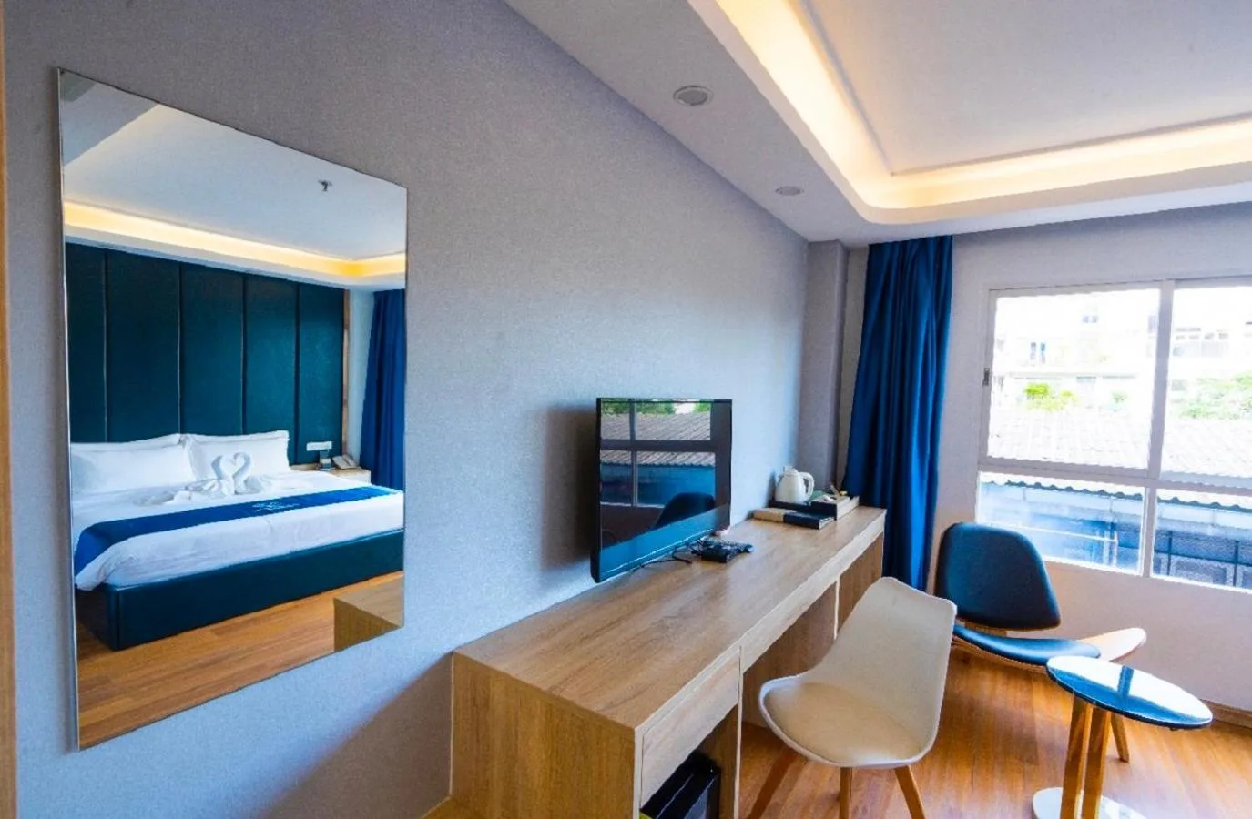 Spacious room interior with desk, seating area, and bed at Sapphire Hotel Silom Bangkok