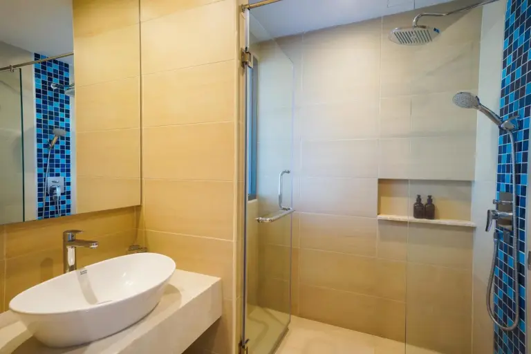 Douche de salle de bains moderne au Seabed Grand Hotel Phuket à Phuket avec paroi vitrée, murs carrelés et douchette.