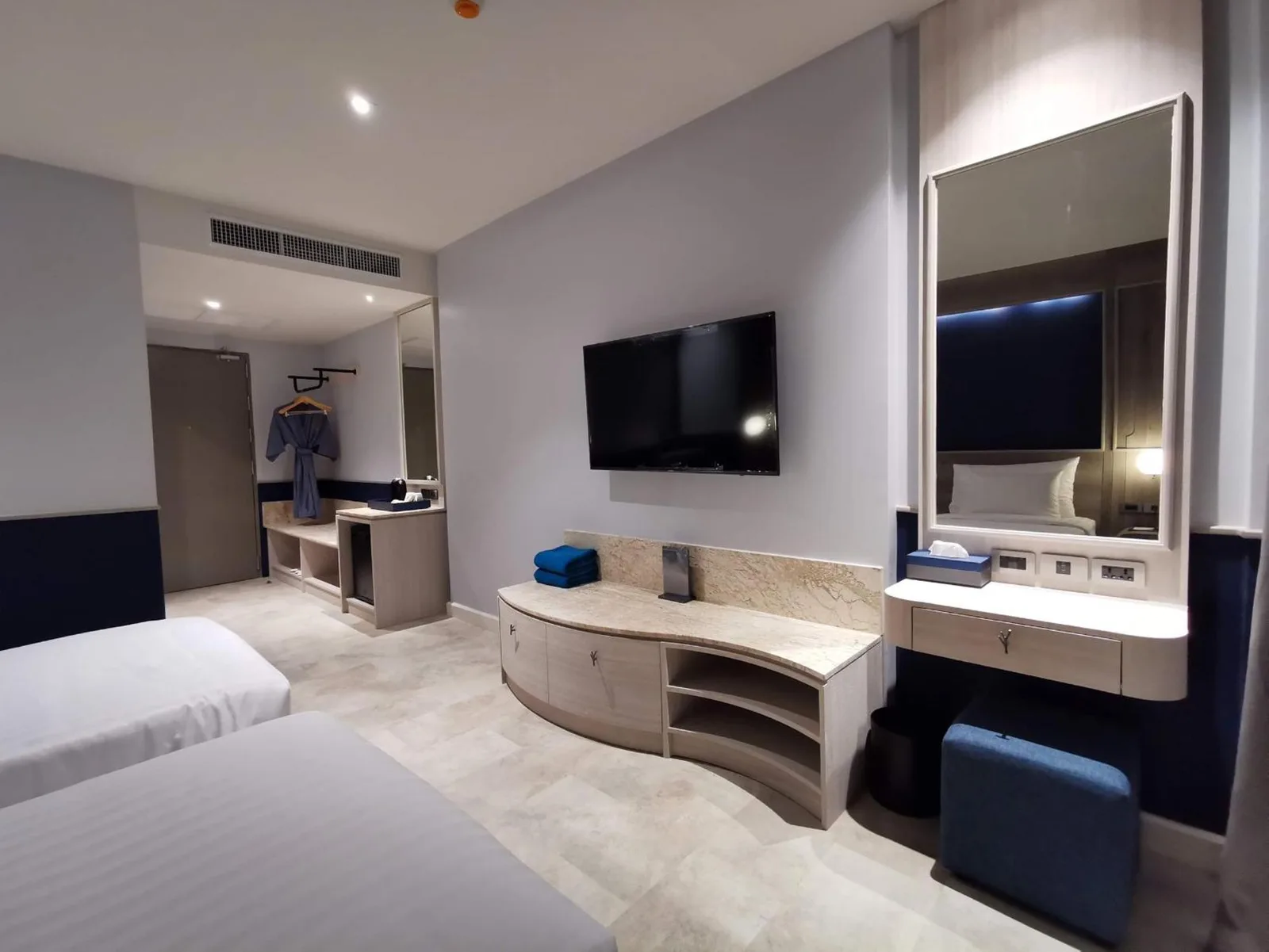 Intérieur moderne d’une chambre au Seabed Grand Hotel Phuket à Phuket avec lits, télévision, coiffeuse et espace armoire.