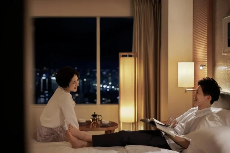 Pareja relajándose en la habitación del Sheraton Grand Hiroshima Hotel por la noche