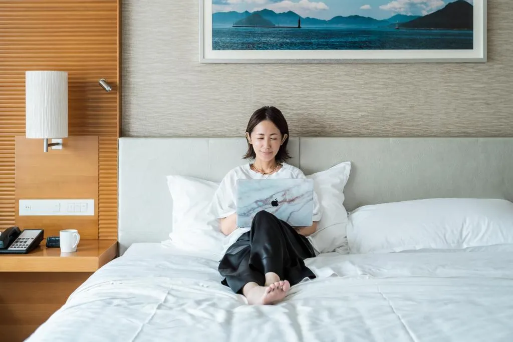 Mujer relajándose en la cama en el Sheraton Grand Hiroshima Hotel