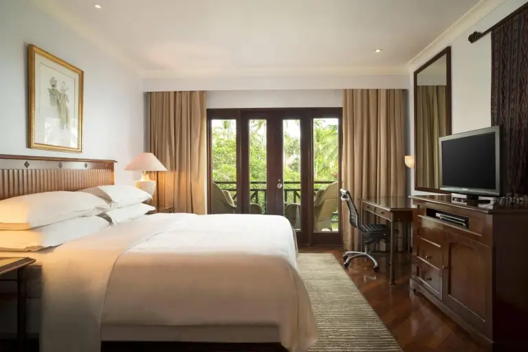 Bright guest room at Sheraton Senggigi Beach Resort in Mataram with a king bed, balcony doors, and work desk.