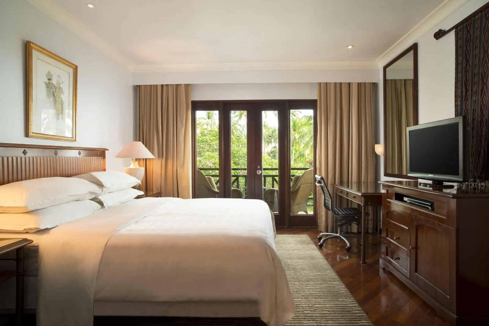 Bright guest room at Sheraton Senggigi Beach Resort in Mataram with a king bed, balcony doors, and work desk.
