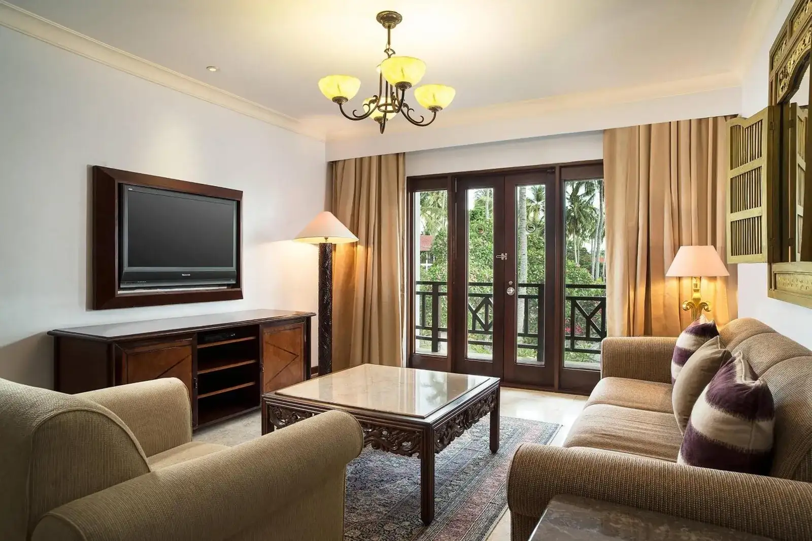 Spacious suite living room at Sheraton Senggigi Beach Resort in Mataram with sofas, TV, coffee table, and balcony view.