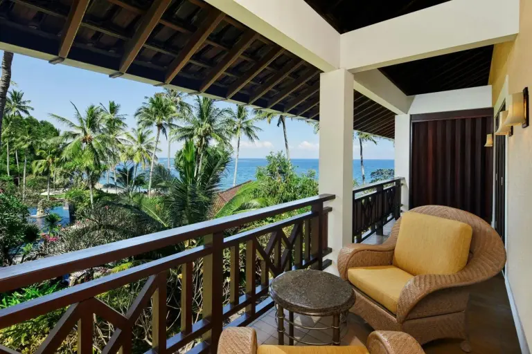 Covered balcony at Sheraton Senggigi Beach Resort in Mataram overlooking the ocean and tropical garden.