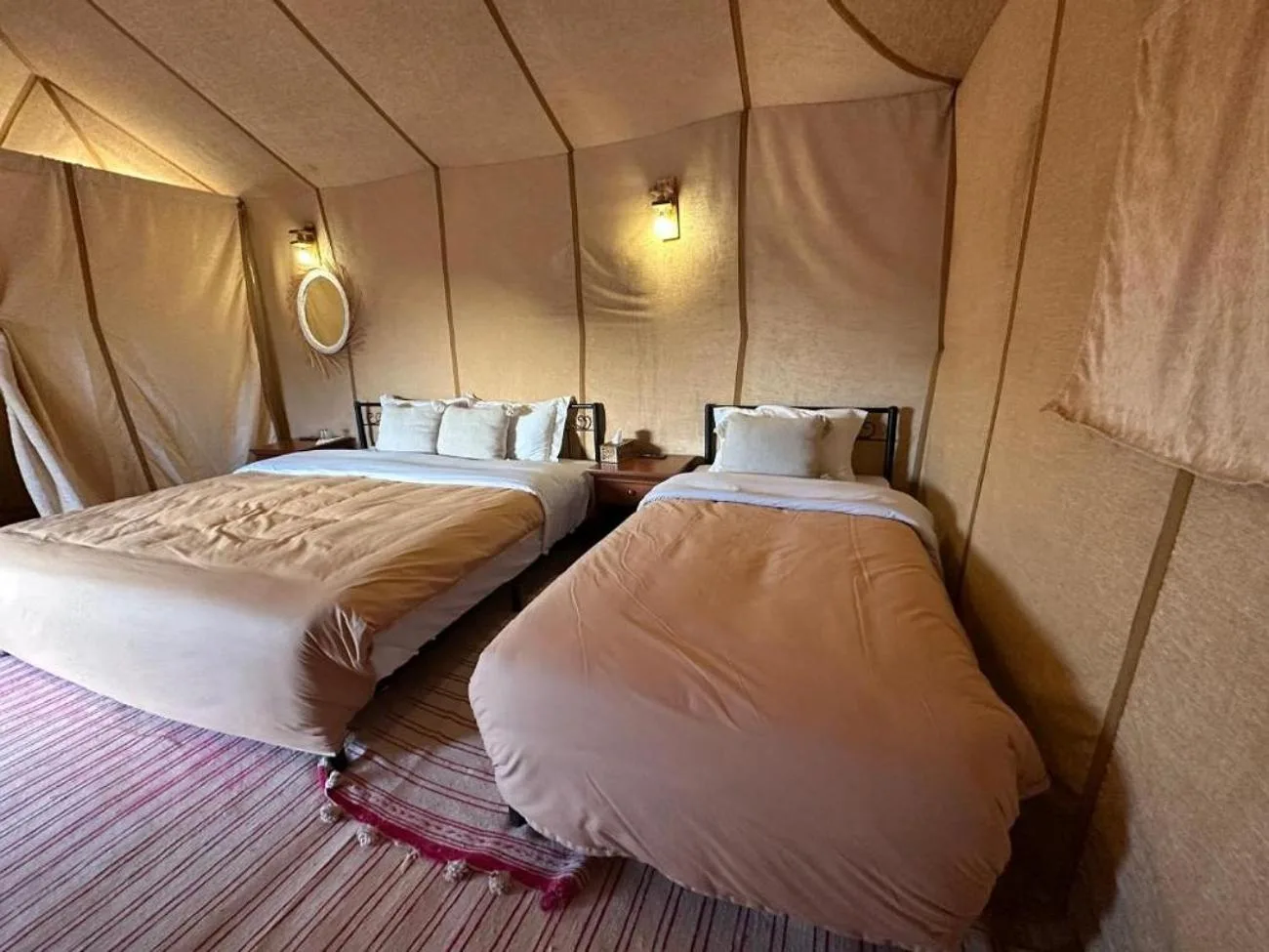 Twin tent room at Shining Luxury Camp in Merzouga with two beds, rugs, and soft beige walls