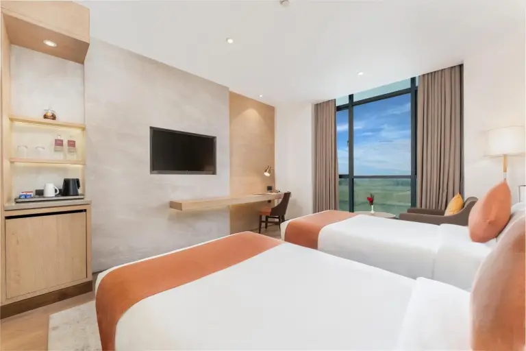 Habitación de huéspedes doble en Siddhartha Vilasa Bhairahawa en Lumbini con dos camas, sillón y distribución espaciosa