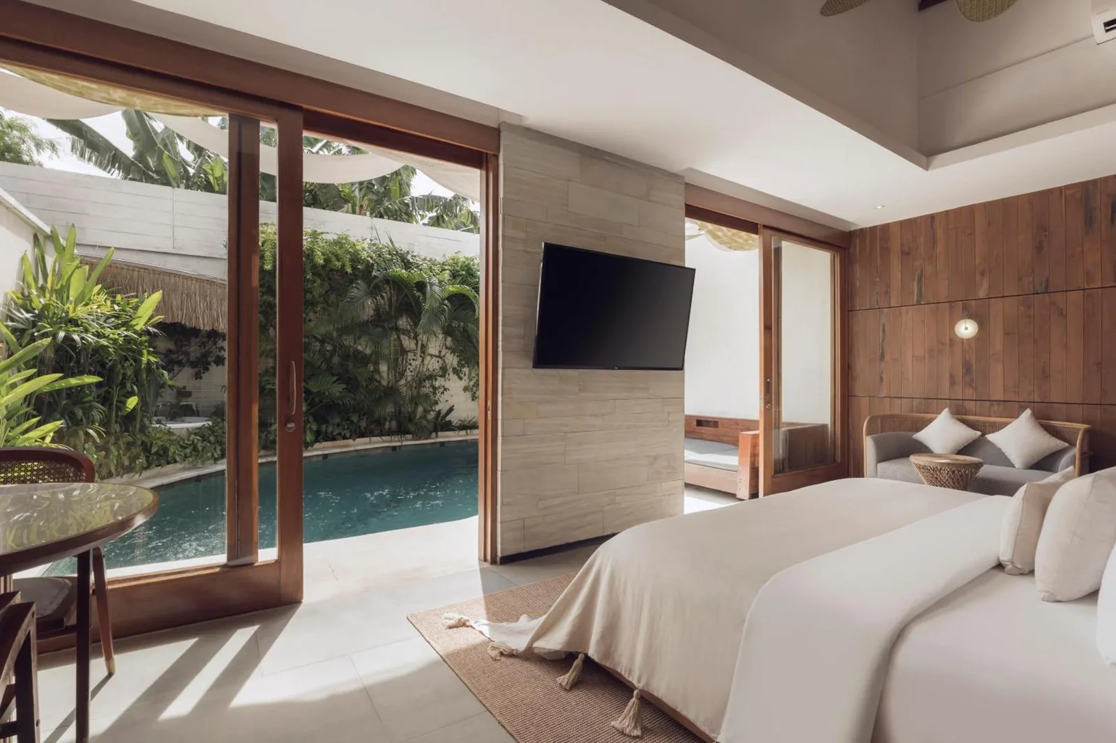 Sini Vie Resort & Spa Seminyak by Ini Vie Hospitality – hotel en Seminyak, Indonesia – un dormitorio con una gran cama blanca y paredes de madera en Sini Vie Resort & Spa Seminyak by Ini Vie Hospitality en Seminyak