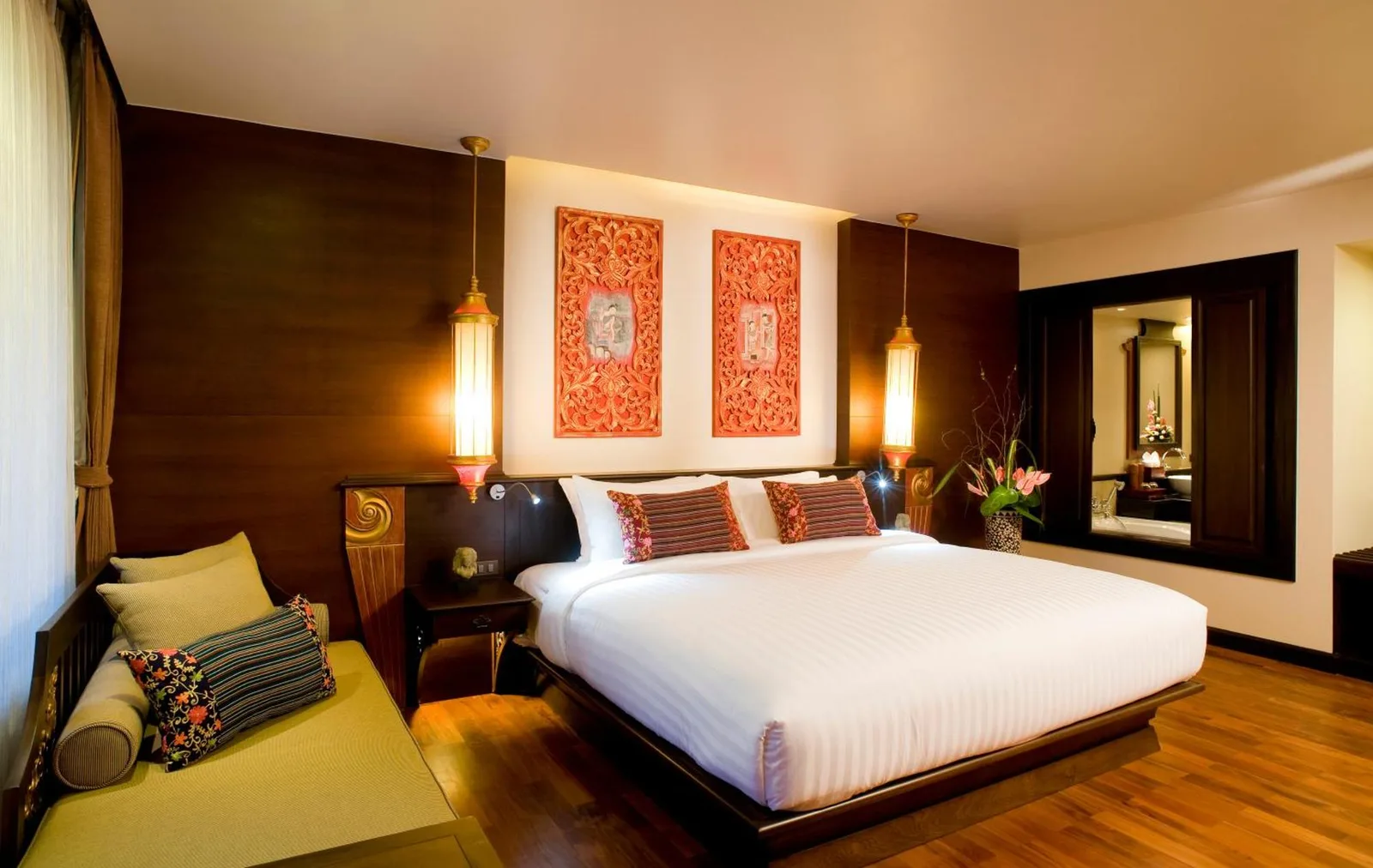 Dormitorio king en Siripanna Villa Resort & Spa Chiang Mai -SHA Extra Plus con arte mural de inspiración tailandesa y un banco de asiento.